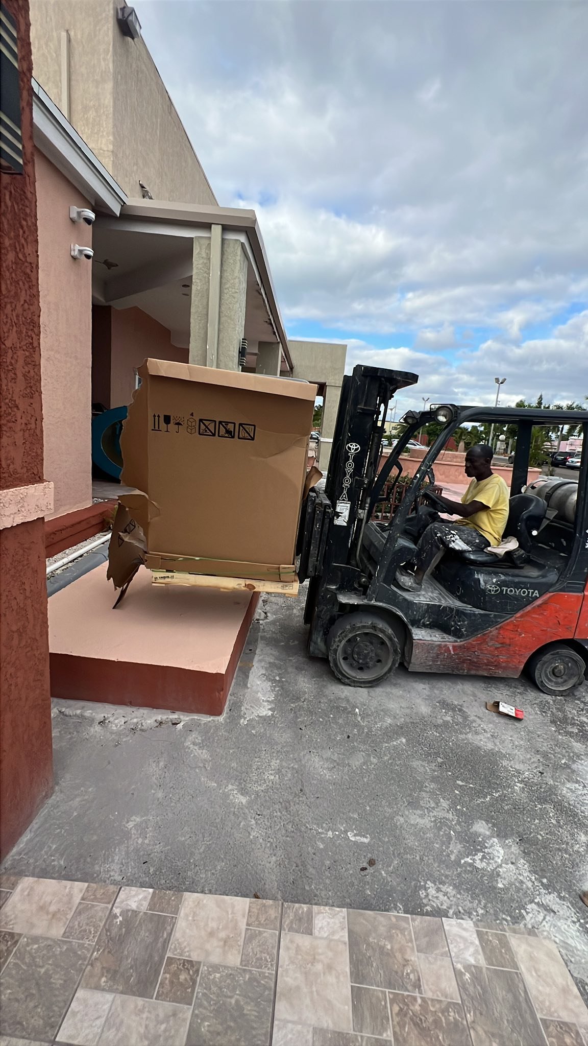 Forklift delivering large commercial AC unit to a Nassau property